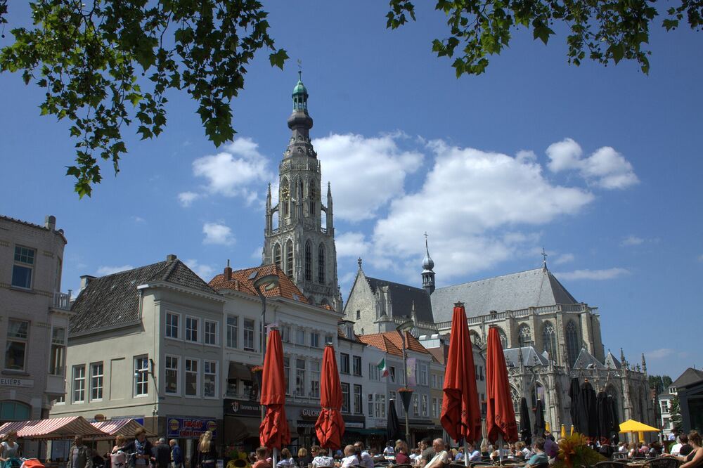 De Grote Markt in Breda met rode parasols en de toren van de Grote Kerk